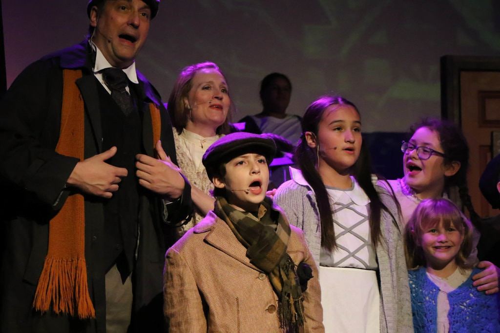 Mike Mazur as Bob Cratchit, Jonathan Rizzo as Tiny Tim, and others in Scrooge the Musical