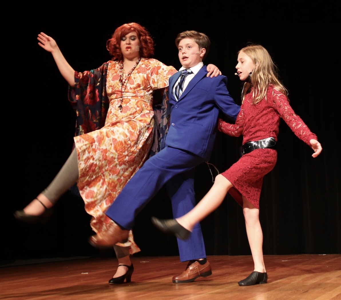 three youth actors perform kickline on stage in performance of Annie JR at the Palace Arts Center in Grapevine