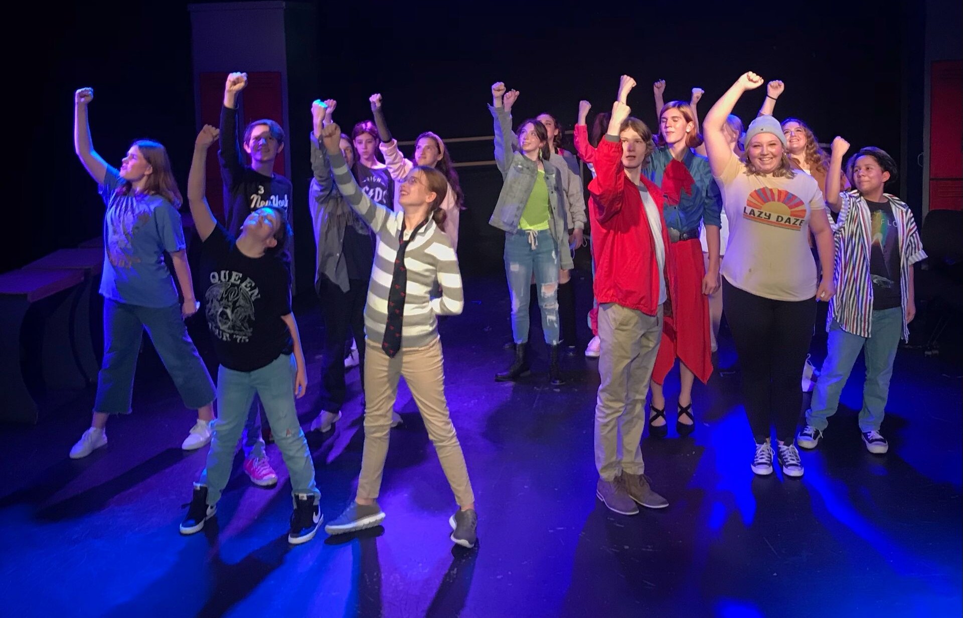 NTPA Academy actors stand together on stage fist pumping in a choreographed dance