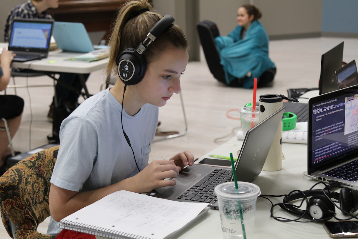 Young girl with headphones working on a laptop