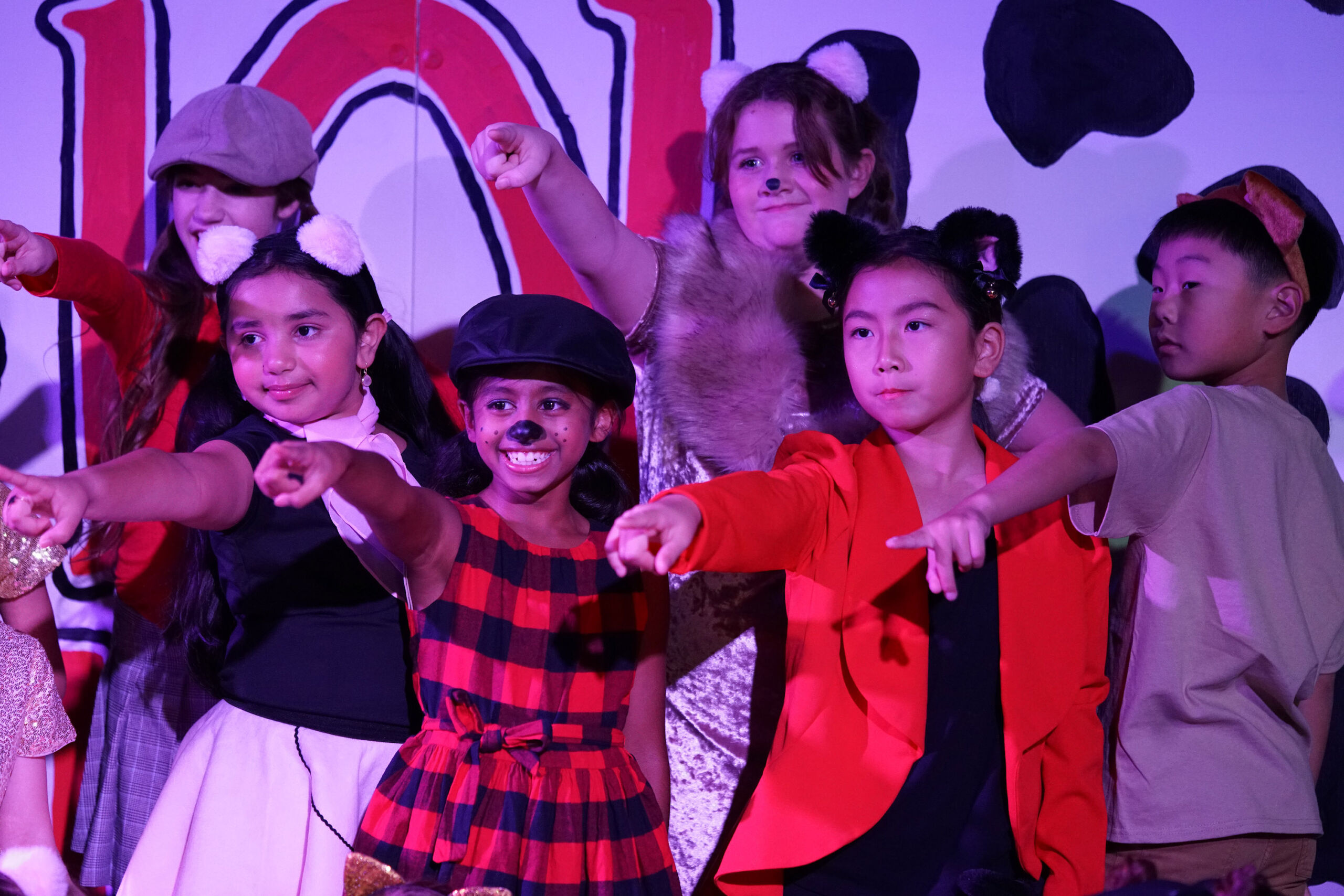 Students pointing on stage in performance of 101 Dalmatians Kids