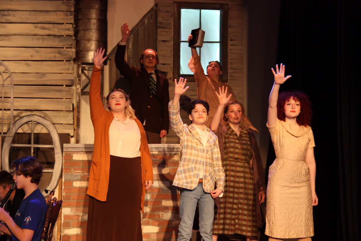 Academy students perform on stage with hands raised during a 2024 production of Bonnie and Clyde